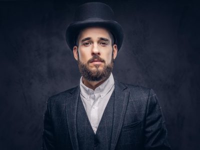 portrait-stylish-bearded-male-elegant-suit-cylinder-hat-looking-camera-dark-background_613910-11377