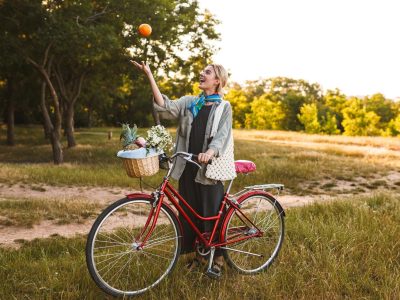 young-smiling-girl-with-red-bicycle-wildflowers-fruits-basket-happily-playing-with-orange-park_574295-3242